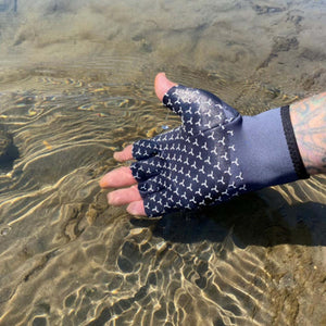 Hand wearing a fingerless patterned glove submerged in shallow water