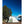 White dome tent set up on rocky ground next to a large tree under a clear blue sky