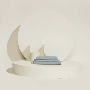 Folded blue Outlast bed sheets on a circular platform