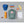Fjallraven Kanken backpack with blue cap, Primus thermos, pens, notebook, banana, apple, and nuts on grey background