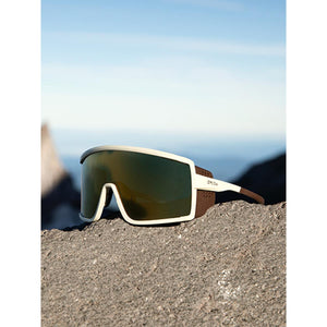 Smith sunglasses with cream frame and brown side shields resting on a rocky surface