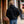 Person wearing a black hooded sweatshirt and blue jeans walking on a sidewalk