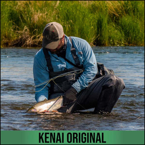 Angler wearing Glacier Glove gear kneeling in a river holding a fish
