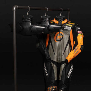 Dainese leather motorcycle racing suit with orange and black accents hanging on a rack