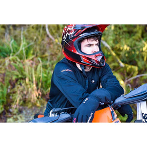 Person wearing ActionHeat black long sleeve shirt and gloves with a motocross helmet leaning on a motorcycle