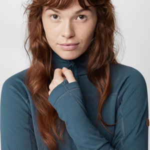Person wearing a blue FjallRaven long sleeve half zip base layer with thumb holes