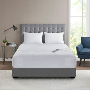White heated mattress pad on a bed with two pillows and dual controllers