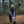 Person in a beanie and grey athletic top stretching their leg on a fallen log in a forest
