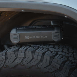 Outdoor Tech portable speaker resting on a rugged off road vehicle tire