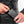 Person plugging a black Racer 10000mAh power bank into a heated jacket pocket