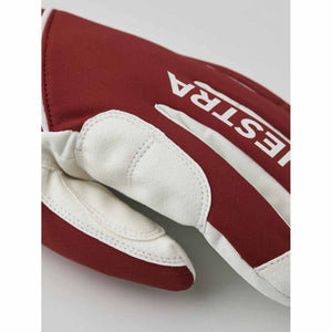 Close up of a red and white Hestra glove with white leather palm detail