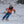 Skier wearing orange jacket and blue pants carving on snow
