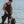 Man wearing Venture Heat vest and wetsuit standing by scuba tank on beach
