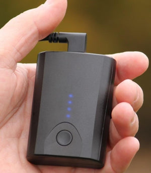 Black portable battery pack with four blue LED indicator lights held in a hand