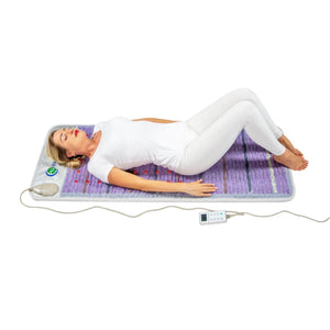 Person lying on a purple infrared therapy mat with a handheld controller