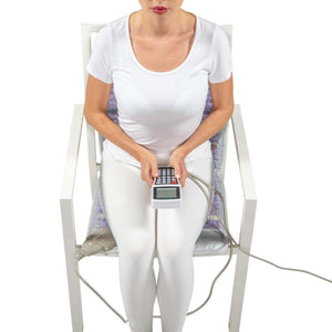 Person sitting on a HealthyLine infrared heating mat holding a digital controller