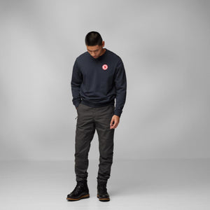 Man wearing a navy FjallRaven sweatshirt and dark grey trousers