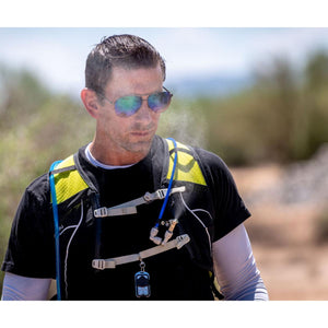 Man wearing a black and yellow hydration vest with a blue tube outdoors