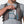 Person placing a smartphone into the zippered chest pocket of a grey Nathan hydration vest