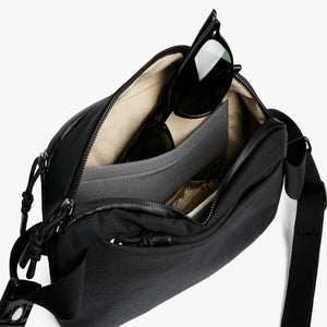 Open Bellroy black crossbody bag with sunglasses inside