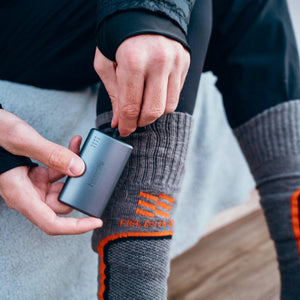 Person connecting a Mobile Warming battery pack to a heated sock