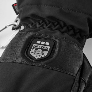 Black Hestra glove with branded rubber patch and metal carabiner