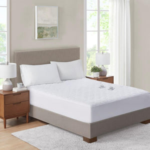 White quilted mattress protector on a bed with two pillows and wooden nightstands
