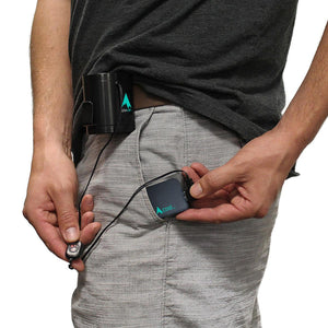 Person wearing an AlphaCool personal cooling device clipped to their waistband with a handheld controller