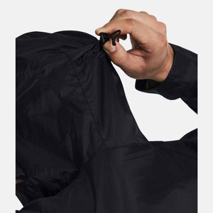 Hand adjusting the drawstring on a black Under Armour jacket hood