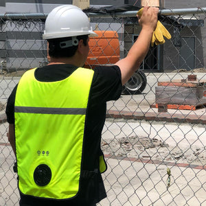Construction worker wearing a white hard hat and a high visibility cooling vest with a built in fan