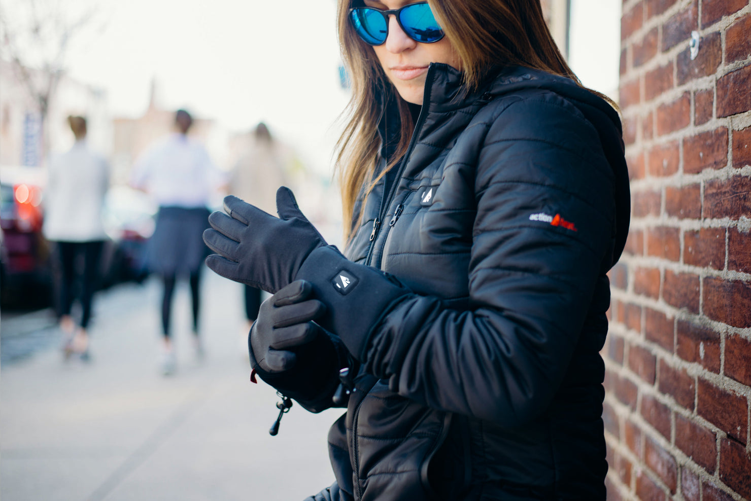 Person wearing ActionHeat black heated gloves and a black puffer jacket
