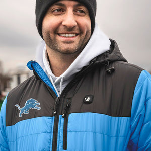 Man wearing a Detroit Lions branded black and blue puffer jacket over a grey hoodie and a black beanie