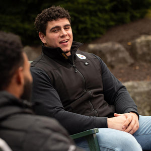 Man wearing a black ActionHeat Steelers heated vest sitting on a park bench