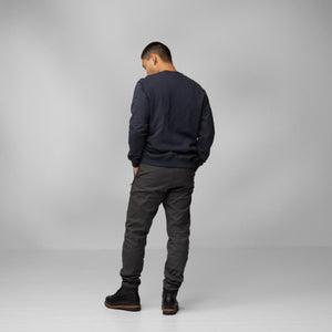 Man wearing a navy sweatshirt and dark grey trousers from behind