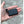 Small black rectangular battery pack with a short power connector cable held in a palm