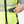Hand placing a grey rectangular device into the pocket of a high visibility neon yellow safety vest