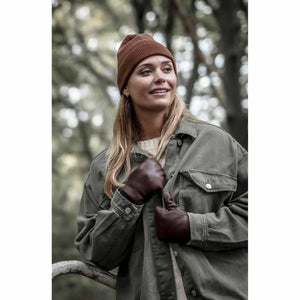 Woman wearing a brown ribbed beanie and dark brown leather gloves with an olive green jacket