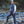 Man wearing a black puffer vest white long sleeve shirt and The North Face cap standing by a rocky stream