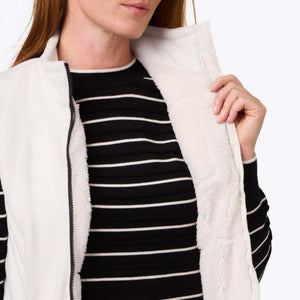 Mobile Warming white fleece vest worn over a black and white striped sweater