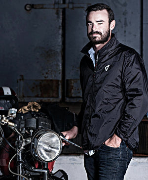 Man wearing a black Gerbing jacket standing next to a motorcycle