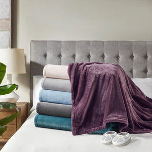 Stack of folded Serta heated blankets in various colors on a bed