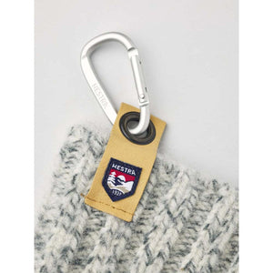 Hestra carabiner attached to a tan leather tab on a grey knit glove