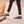 Person wearing grey wool slip on shoes with black soles on a wooden boardwalk