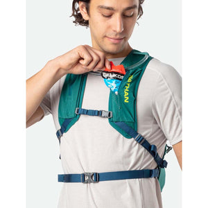Person placing an energy gel packet into the shoulder strap pocket of a green Nathan hydration vest