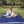 Woman sitting on a blue and black geometric patterned outdoor blanket in a park