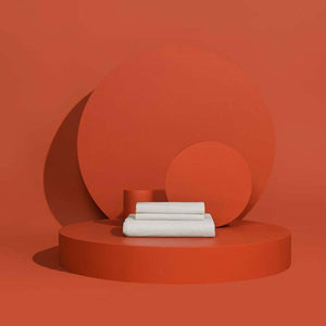 Folded white Outlast bed sheets on a circular orange platform