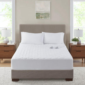 White quilted electric mattress pad on a bed with two white pillows