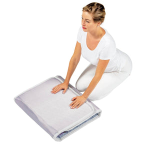 Woman kneeling and touching a folded HealthyLine heating mat