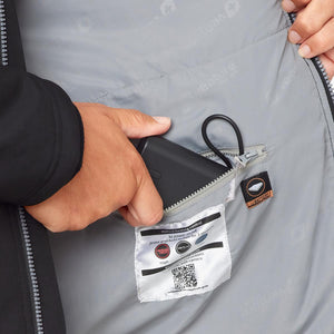 Hand placing battery pack into interior pocket of Venture Heat jacket with heating control instructions