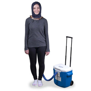Person wearing a cooling head wrap connected to a portable blue rolling cooler unit